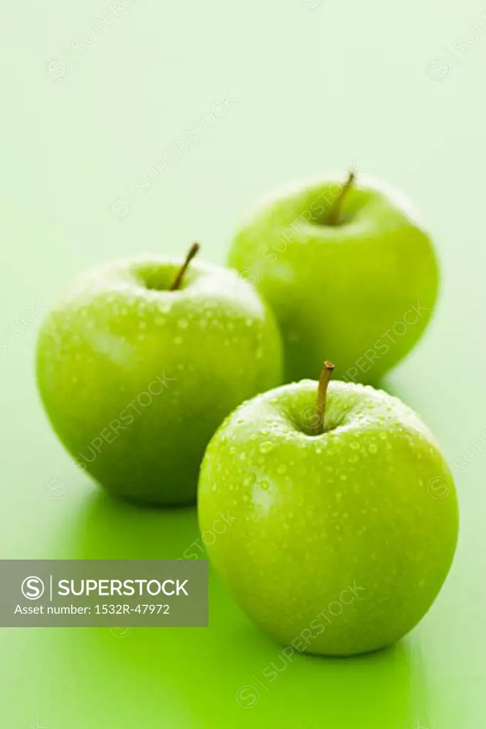 Three Granny Smith apples with drops of water