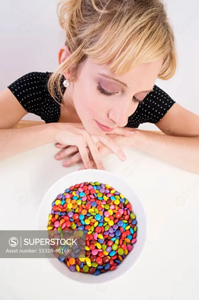 Woman looking pensively at coloured chocolate beans
