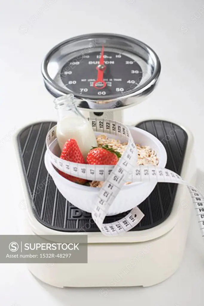Strawberries, milk, cereal and tape measure on scales