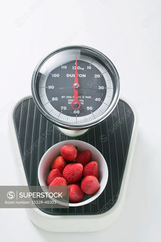Bowl of fresh strawberries on scales