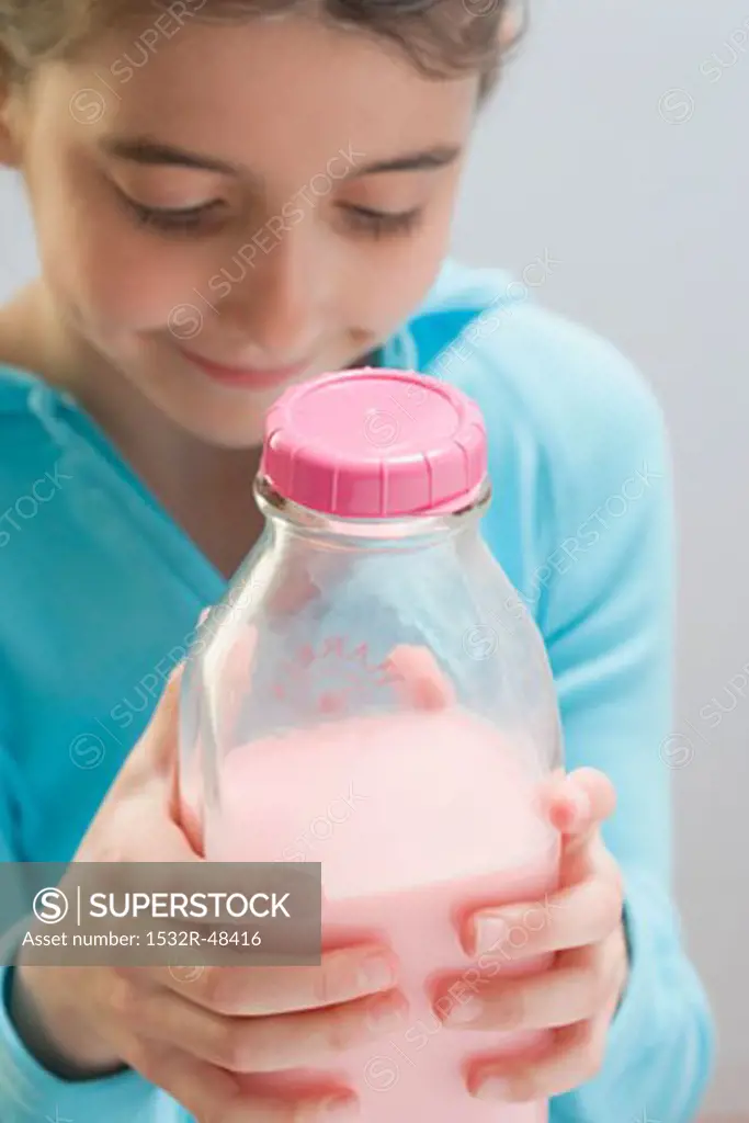 Little girl holding bottle of strawberry milk