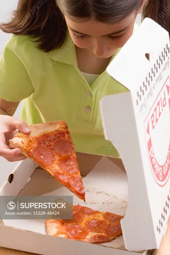 Little girl taking slice of pizza out of pizza box