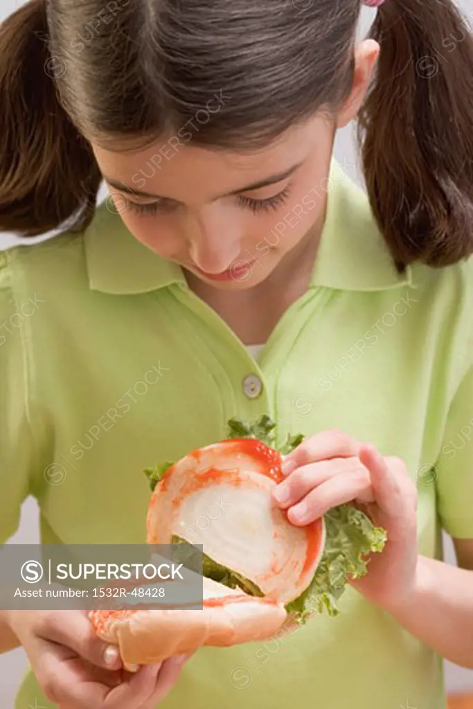 Little girl looking into opened burger