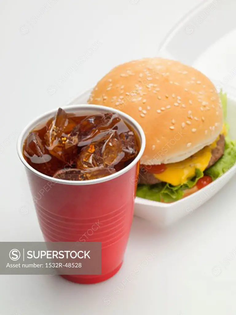Cheeseburger in packaging, cola in plastic cup
