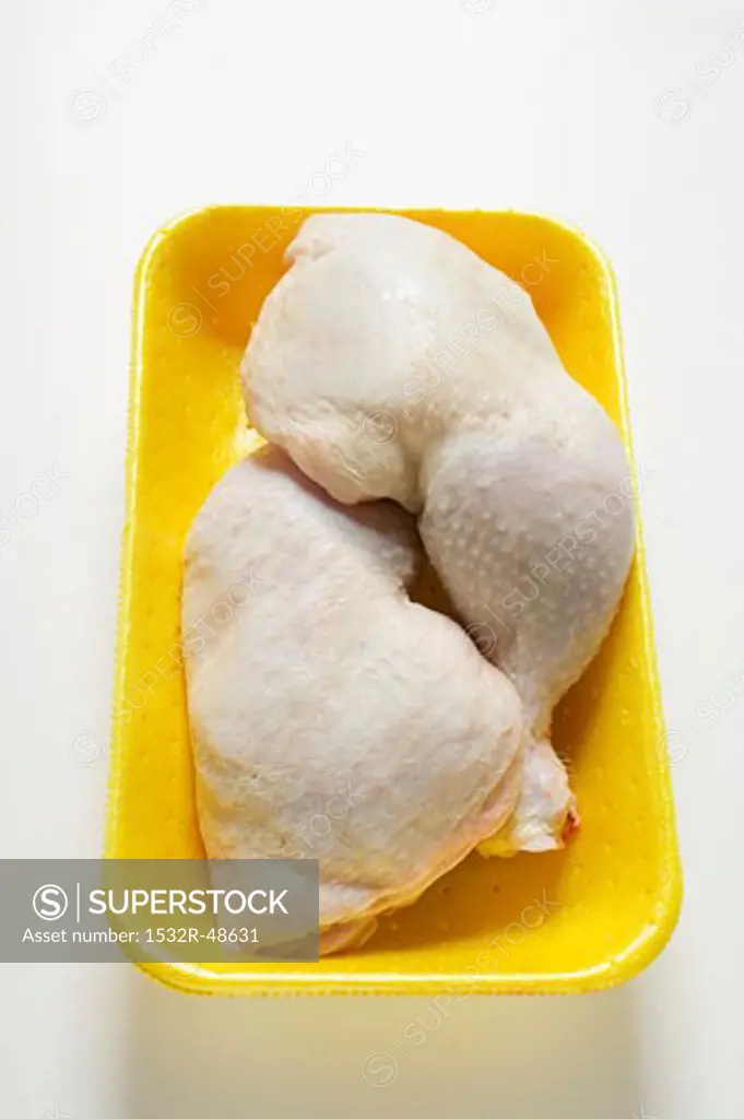 Two fresh chicken legs in polystyrene tray
