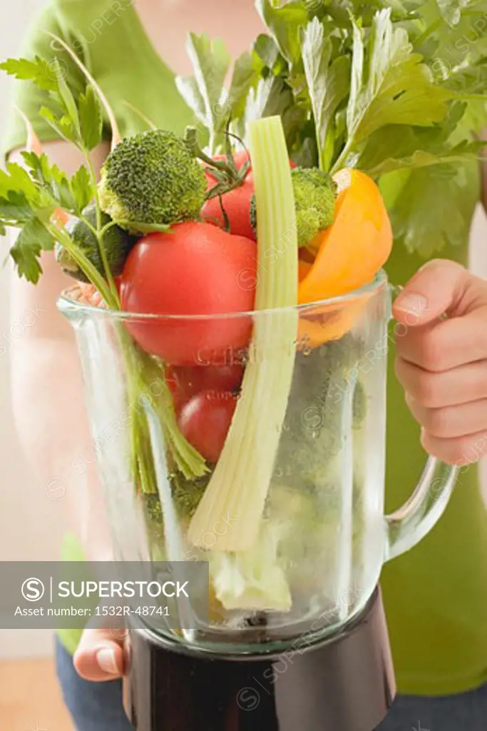 Woman holding fresh vegetables in liquidiser