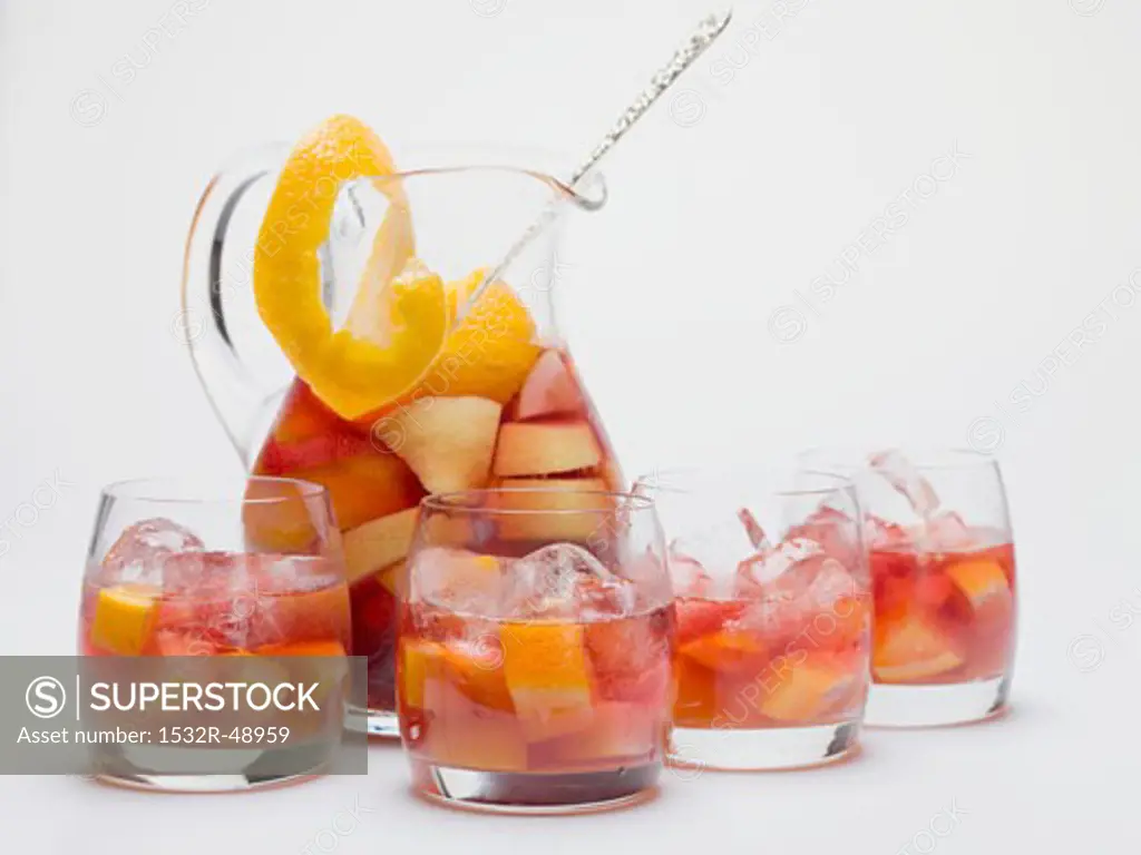 Fruity red wine punch in glass jug and glasses