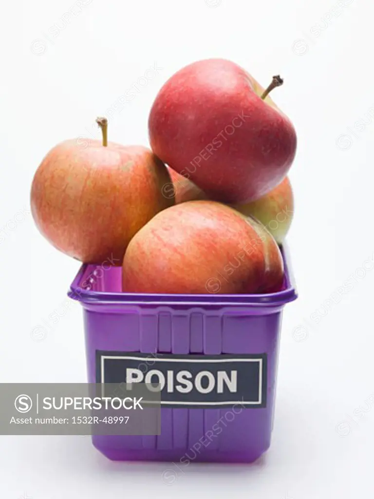 Red apples in a plastic punnet with a 'POISON' label