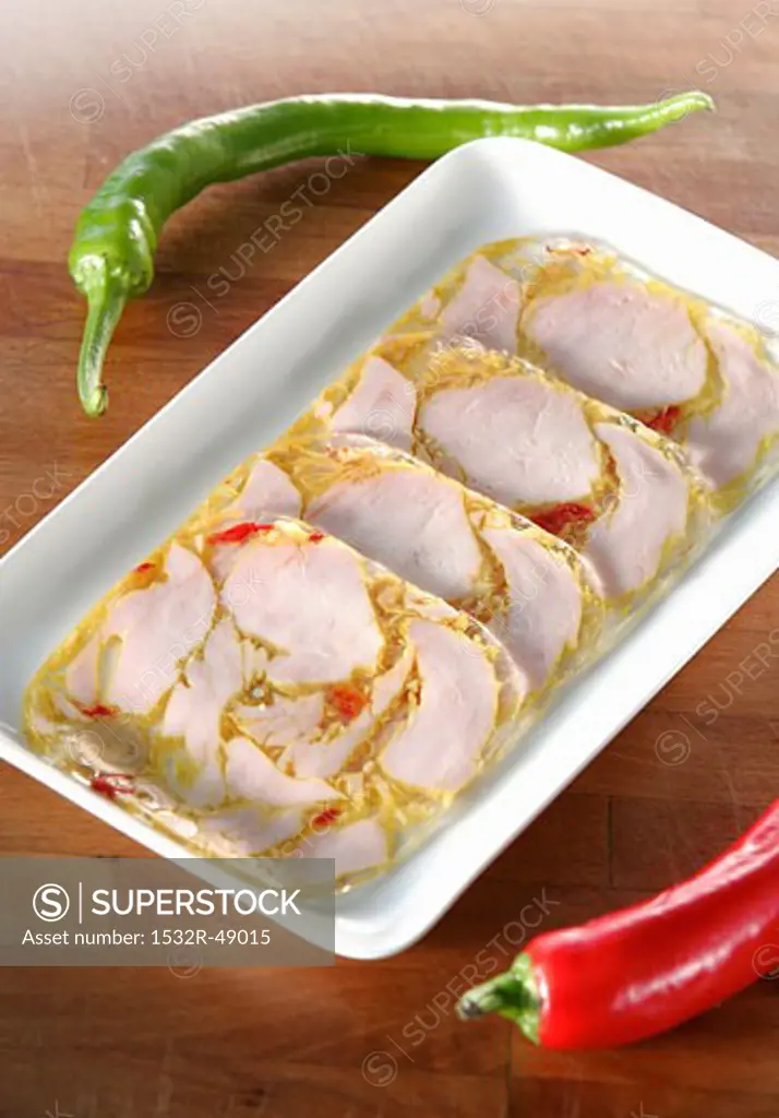 Several slices of turkey breast in jelly, green chilli