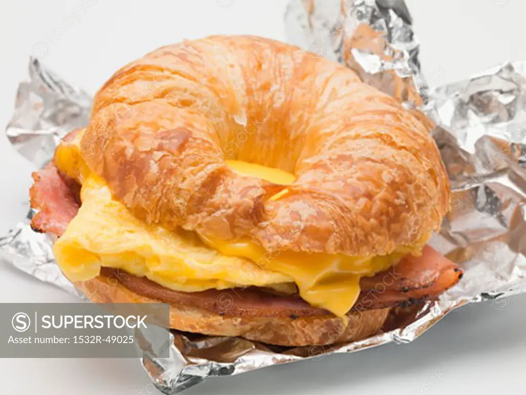 Croissant filled with scrambled egg, cheese & bacon on foil
