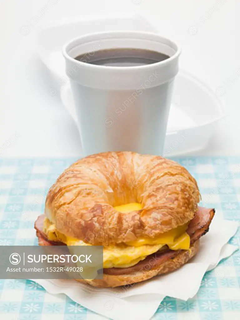 Croissant with scrambled egg, cheese & bacon, cup of coffee