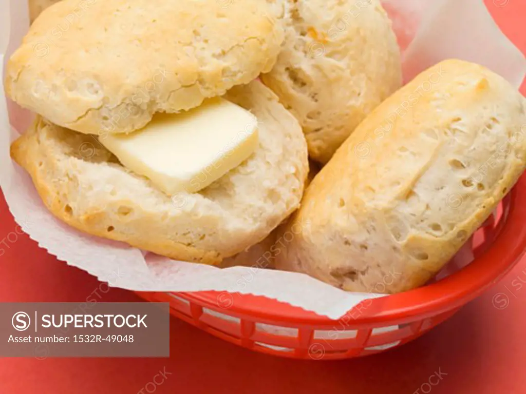 Scones in a plastic basket (one with butter)