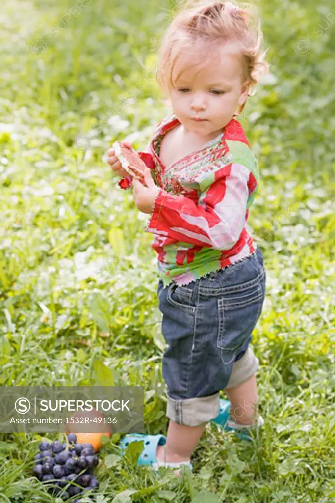 Little girl holding rice cake in grass
