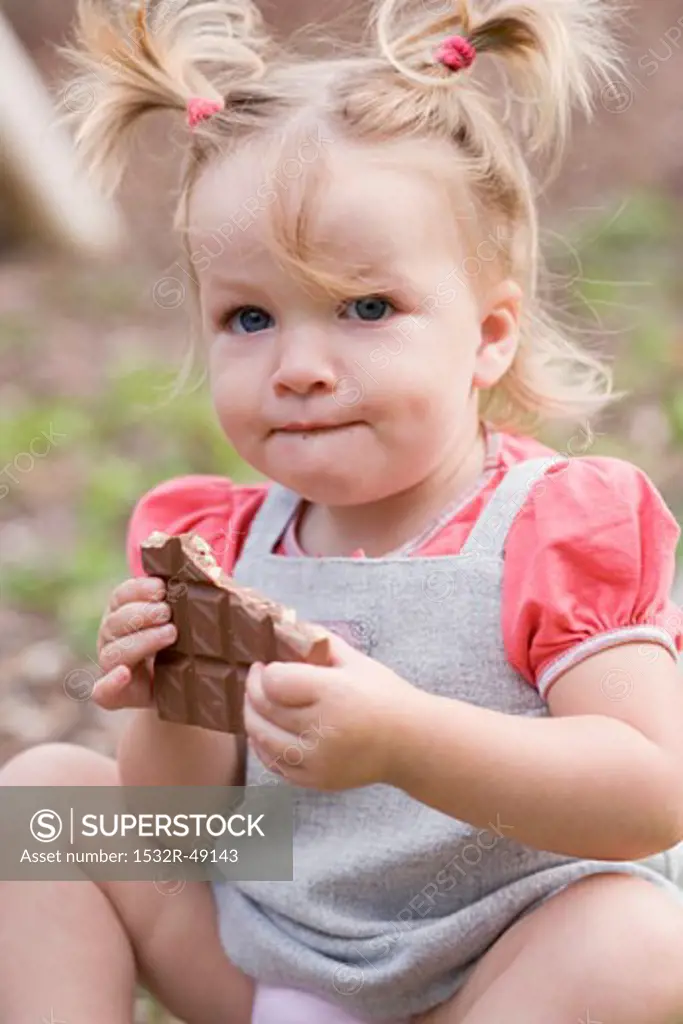 Little girl holding part of a bar of nut chocolate