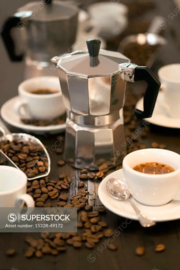 Espresso maker, cups of espresso and coffee beans