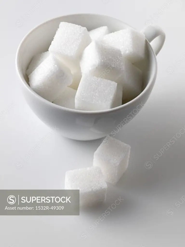 Sugar cubes in and beside white cup
