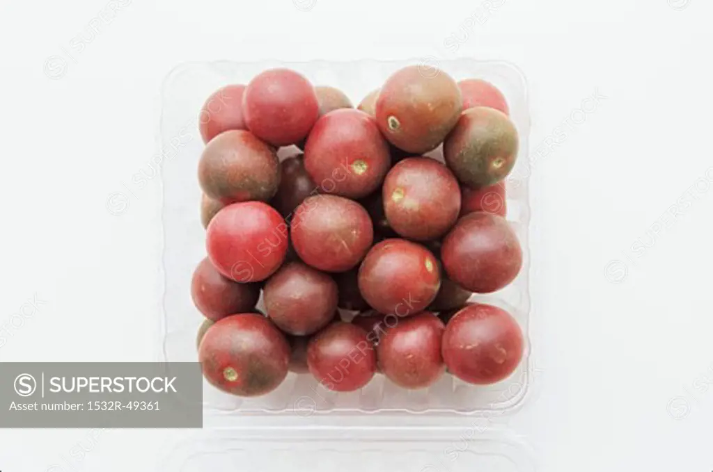 Black cherry tomatoes in a plastic punnet