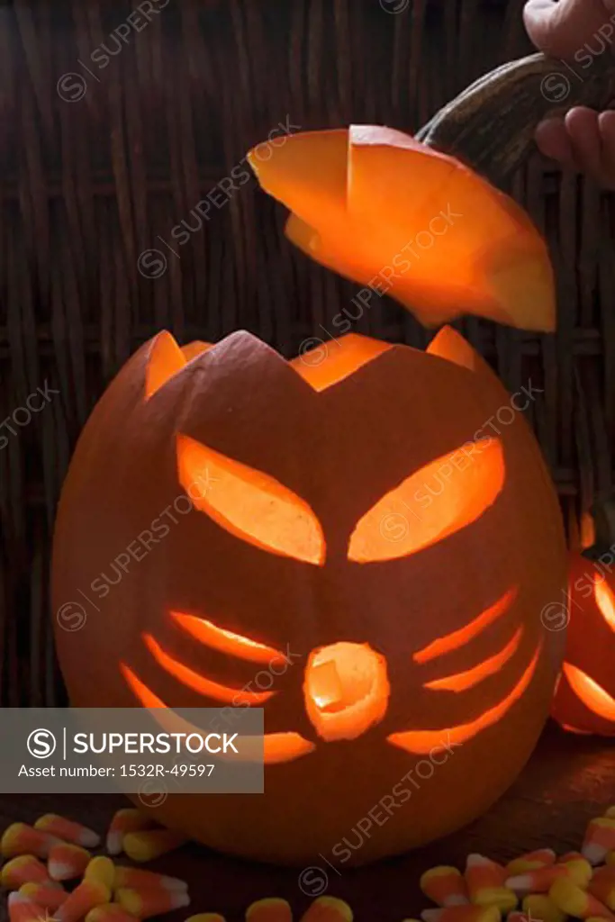 Hand putting lid on pumpkin lantern