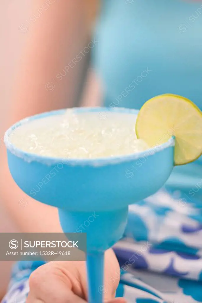 Woman holding cocktail with crushed ice and slice of lime