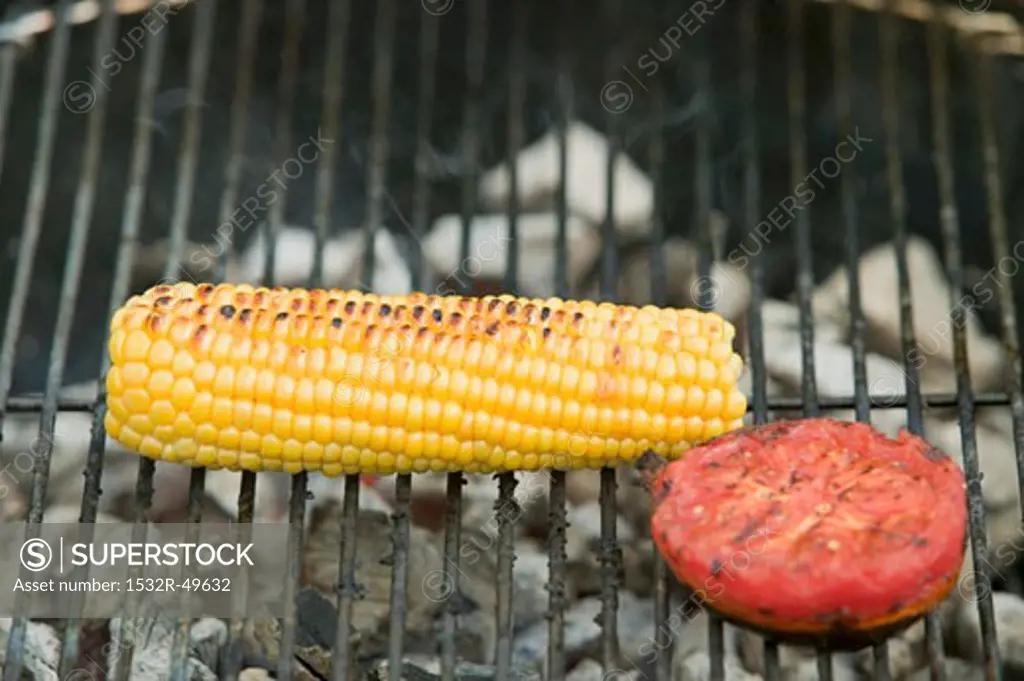 Cob of corn and tomato on a barbecue