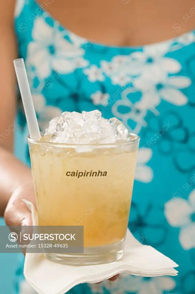 Woman holding cocktail in glass with the word 'Caipirinha'