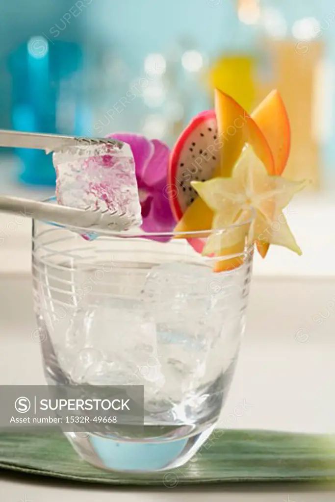 Putting ice cubes into a cocktail glass