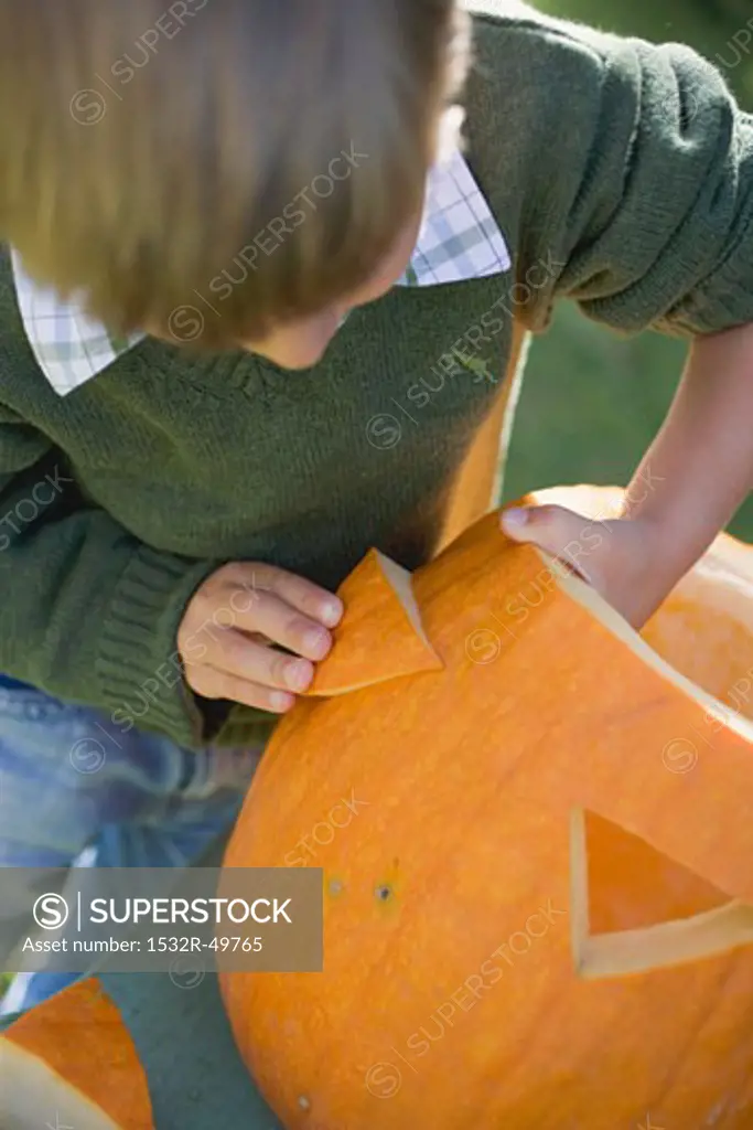 Small boy making pumpkin lantern