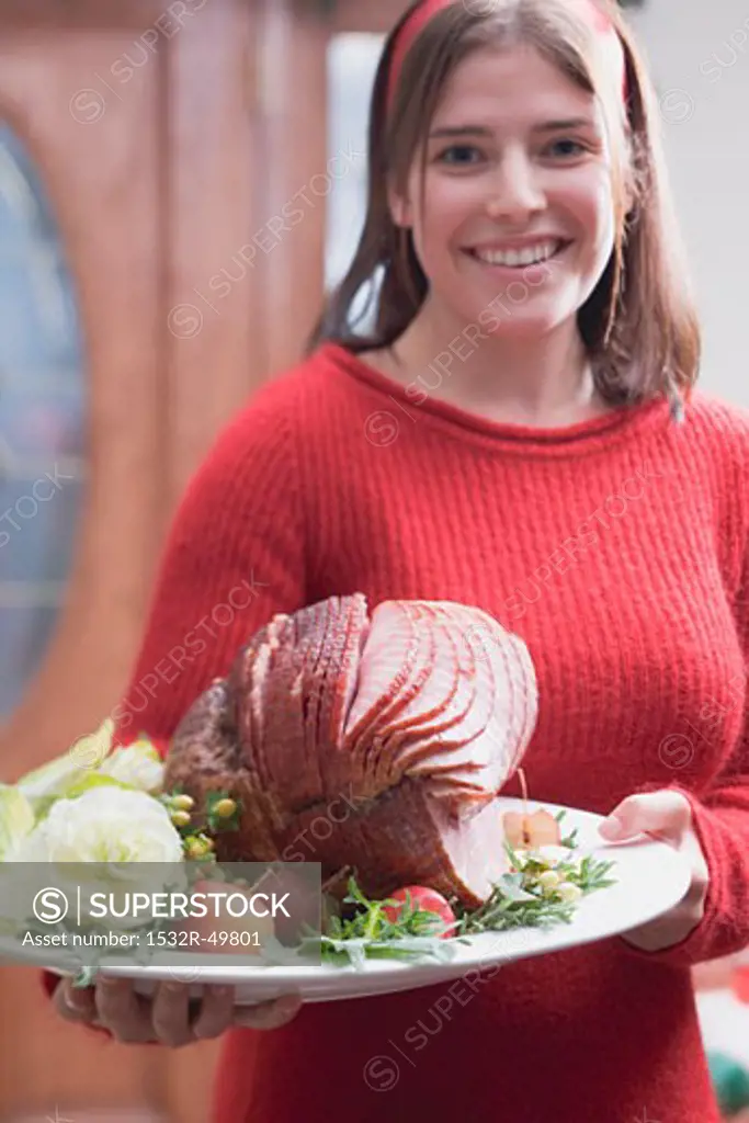 Young woman serving roast ham (Christmas)