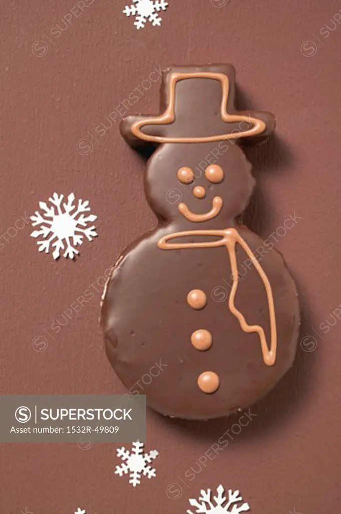 Snowman biscuit with chocolate icing on brown background