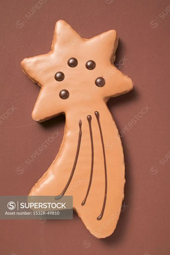 Shooting star biscuit with chocolate icing on brown background