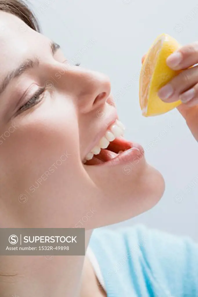 Young woman squeezing lemon juice into her mouth