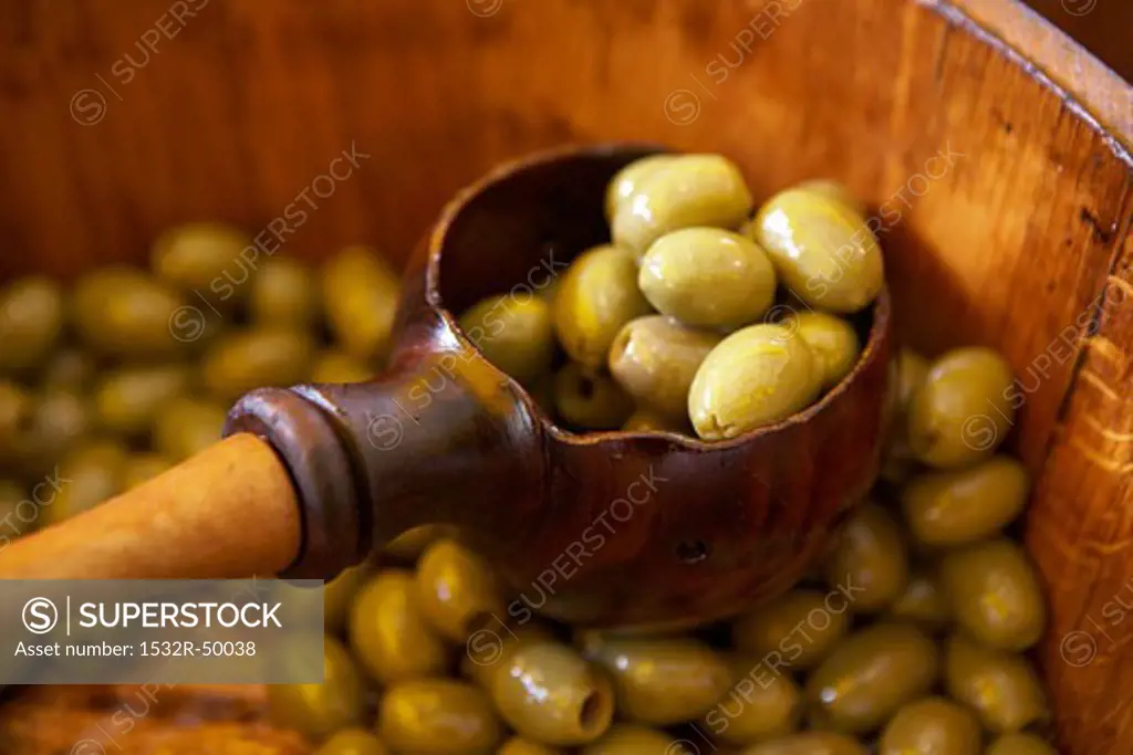Pickled green olives in wooden barrel, scoop