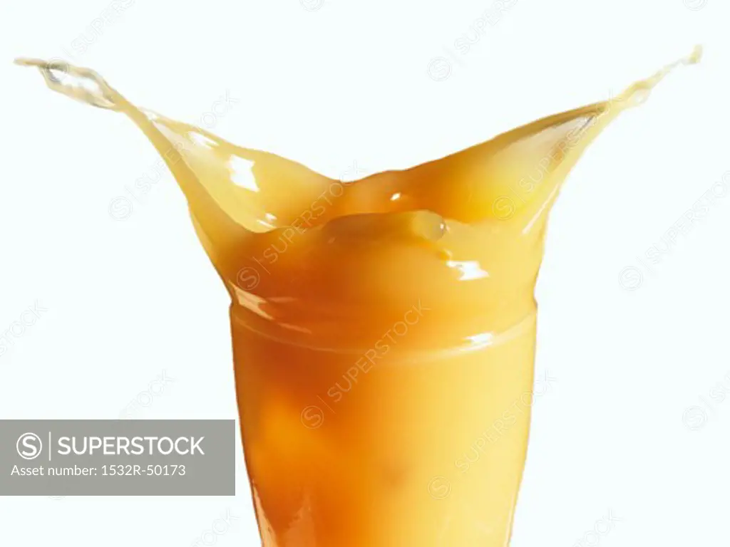 Mango nectar splashing out of a glass