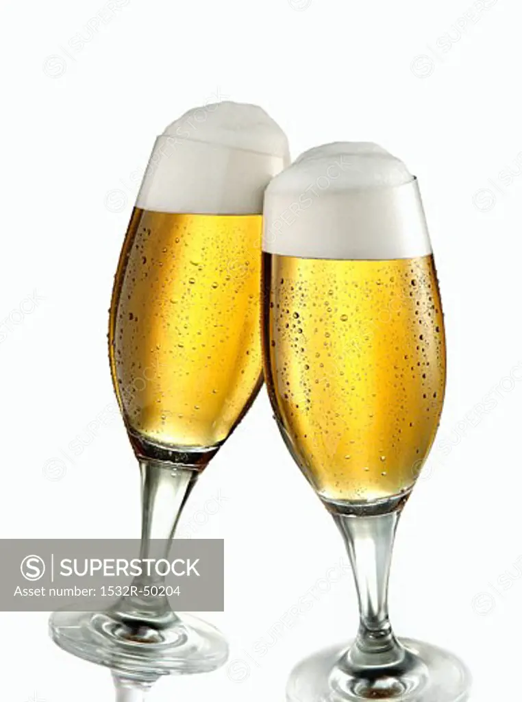 Two glasses of pils clinking together