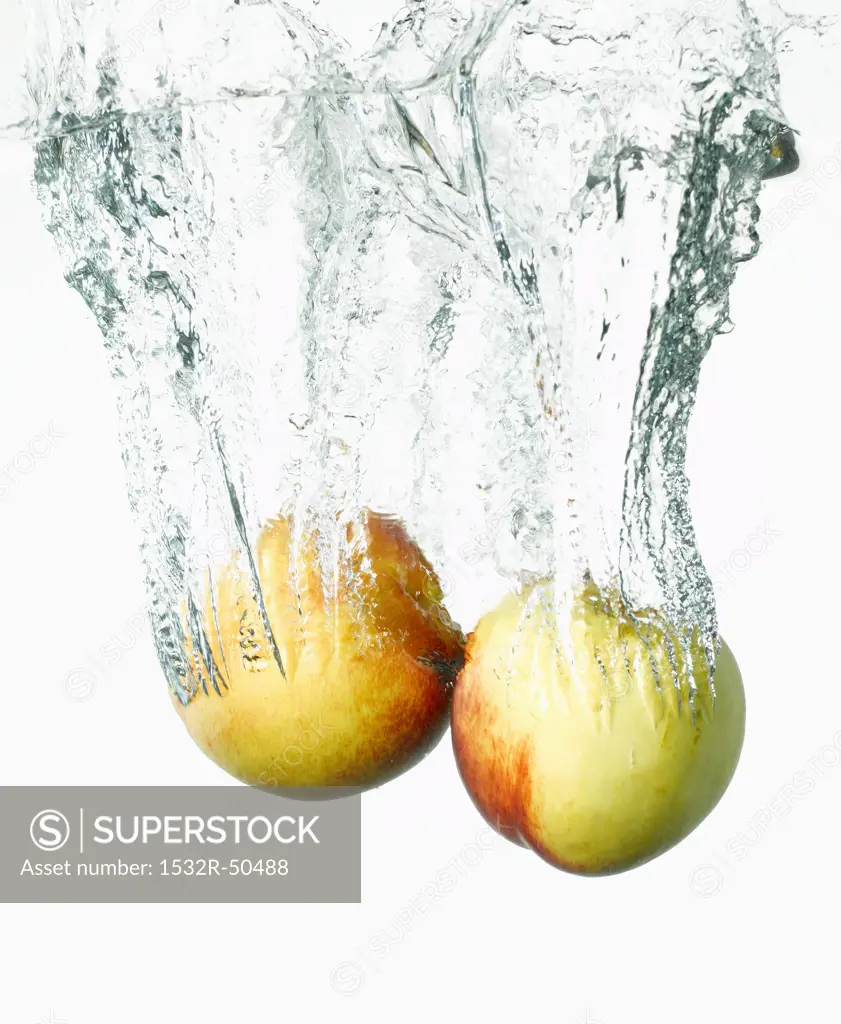 Two nectarines falling into water