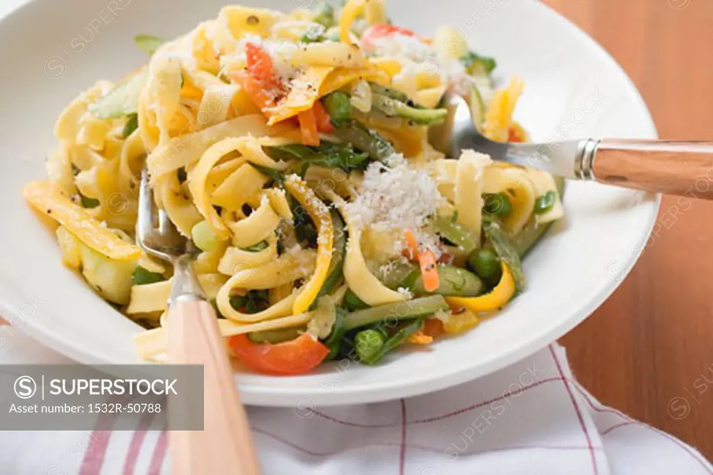 Tagliatelle primavera with vegetables & grated cheese on plate