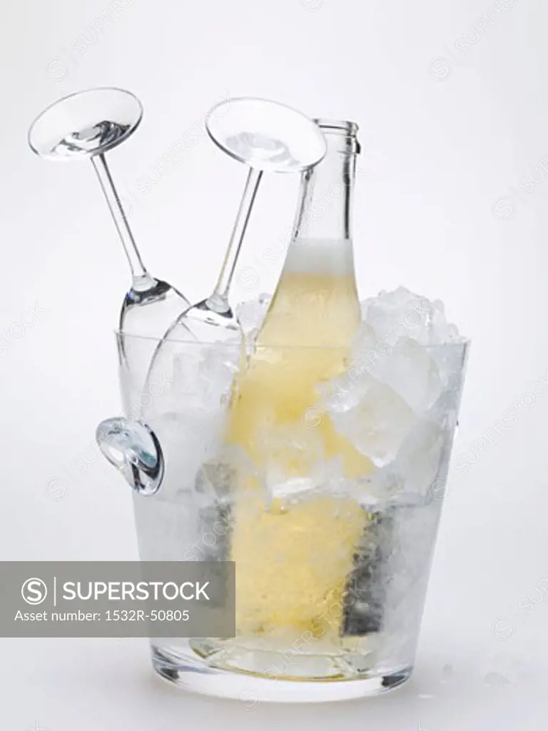 Bottle of sparkling wine & two empty wine glasses in ice bucket