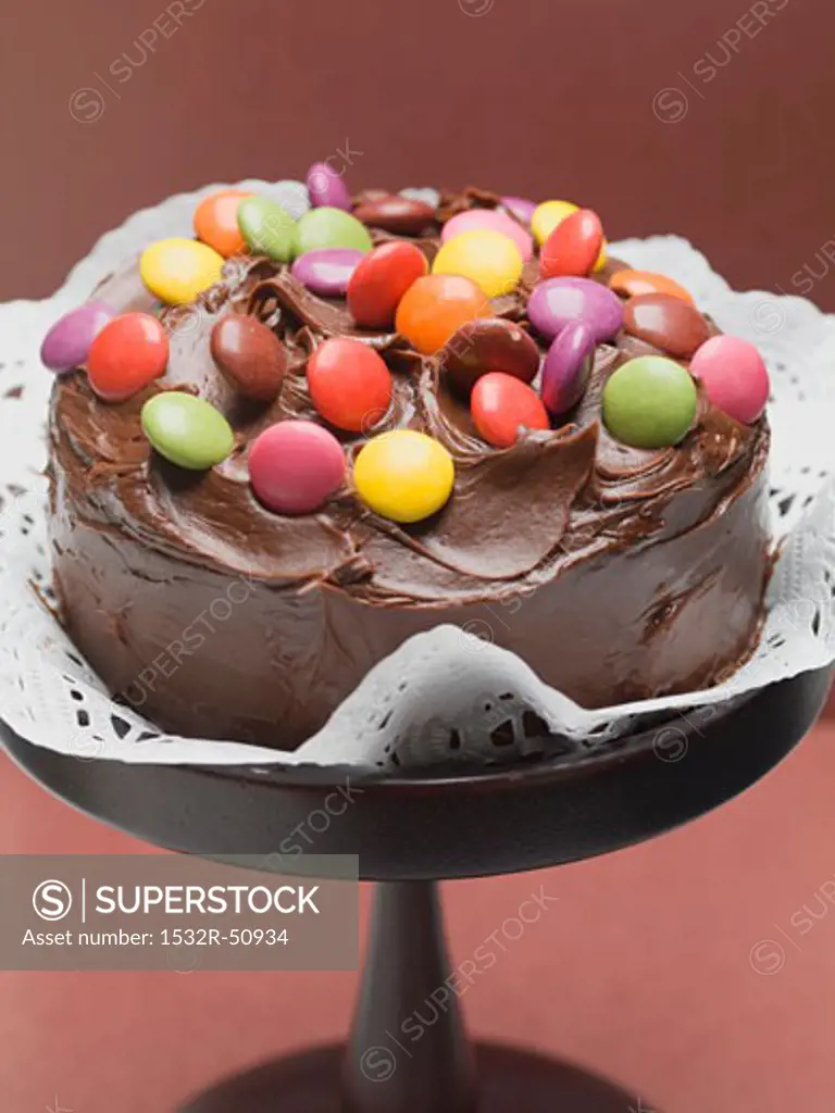 Chocolate cake with coloured chocolate beans on cake stand