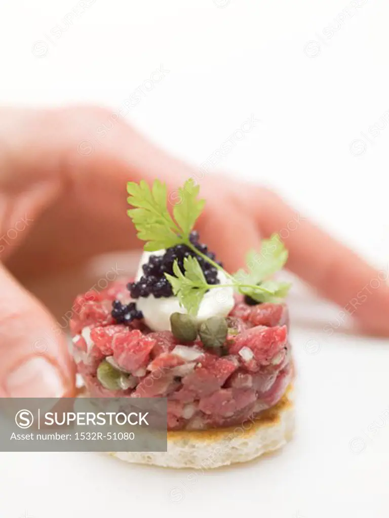 Hand reaching for tuna tartare canapé