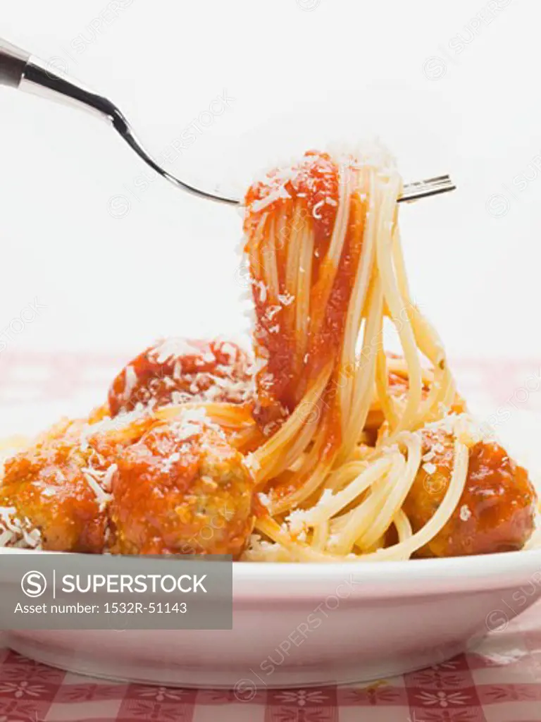 Mixing spaghetti and meatballs in tomato sauce