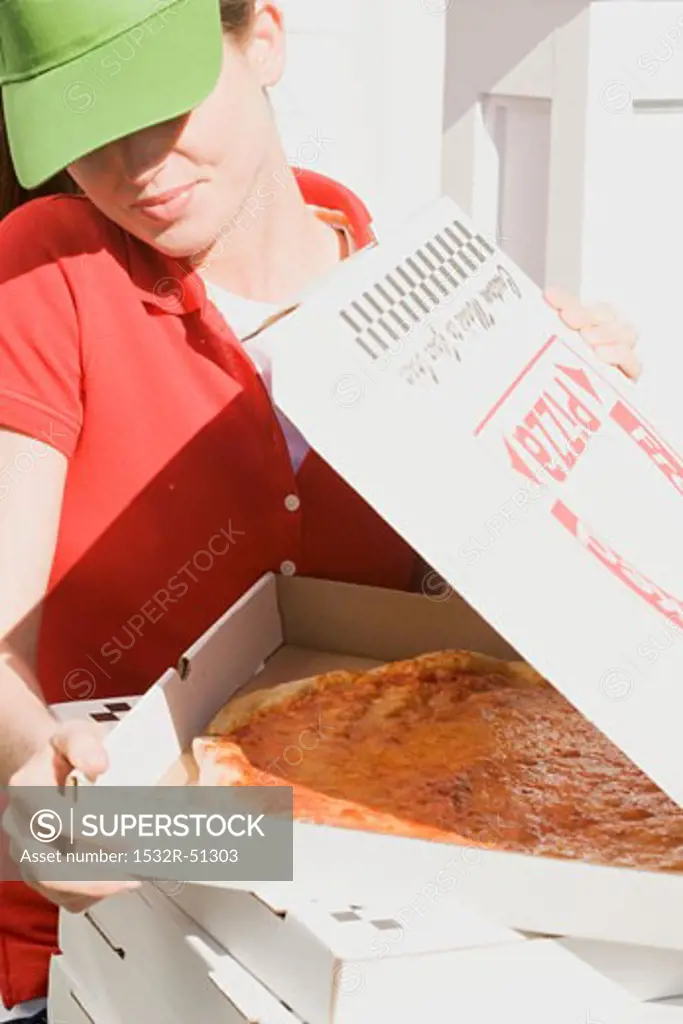 Woman in sun visor looking into opened pizza box
