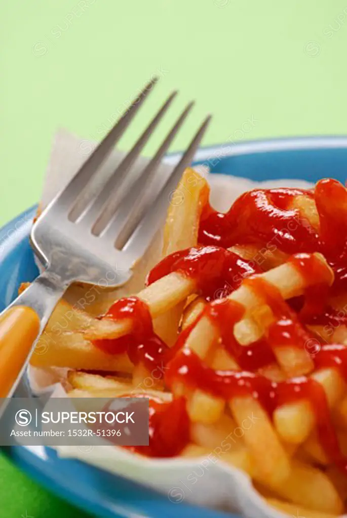 Fork lying beside chips with ketchup