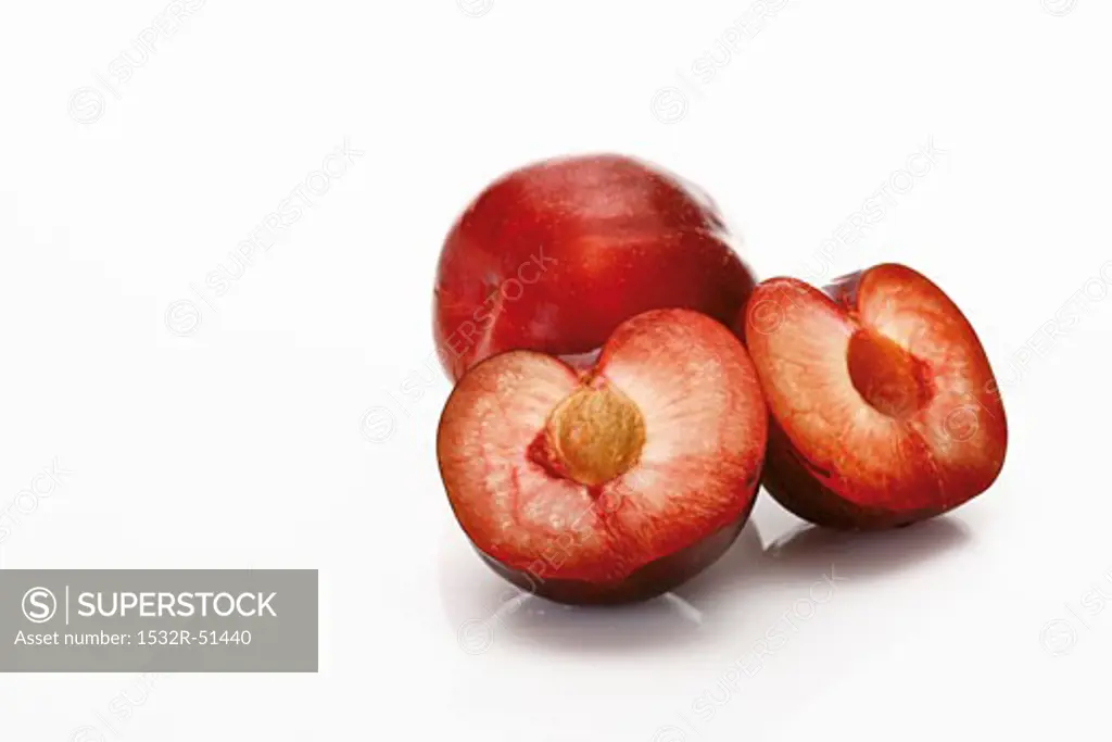 Red plums, one whole and one halved