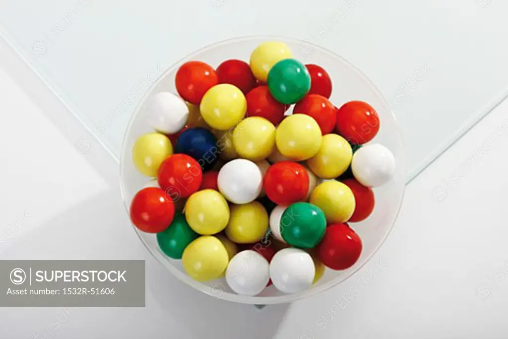 Coloured bubble gum balls in a bowl (overhead view)