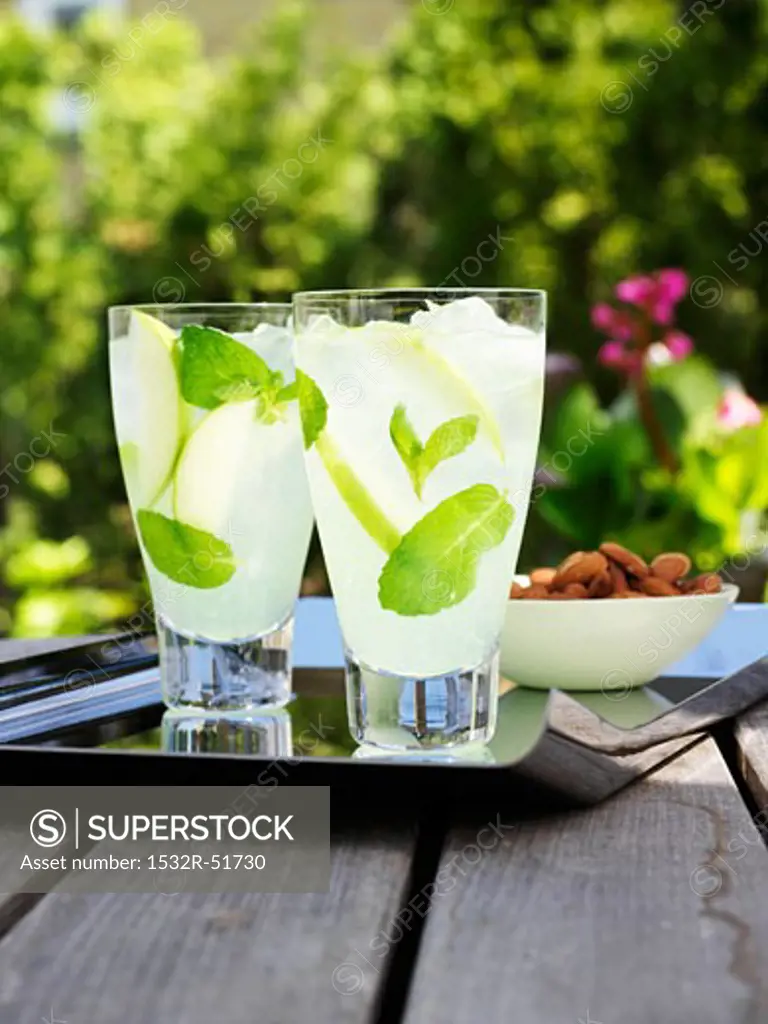 Two glasses of lemonade with fresh mint on table out of doors