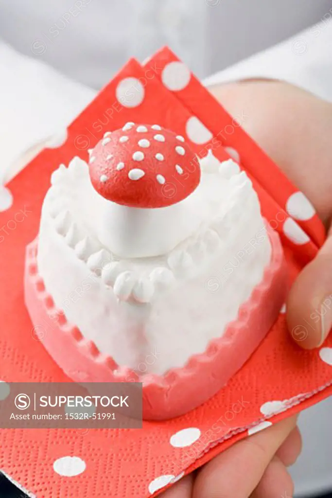 Hands holding small cake with marzipan fly agaric