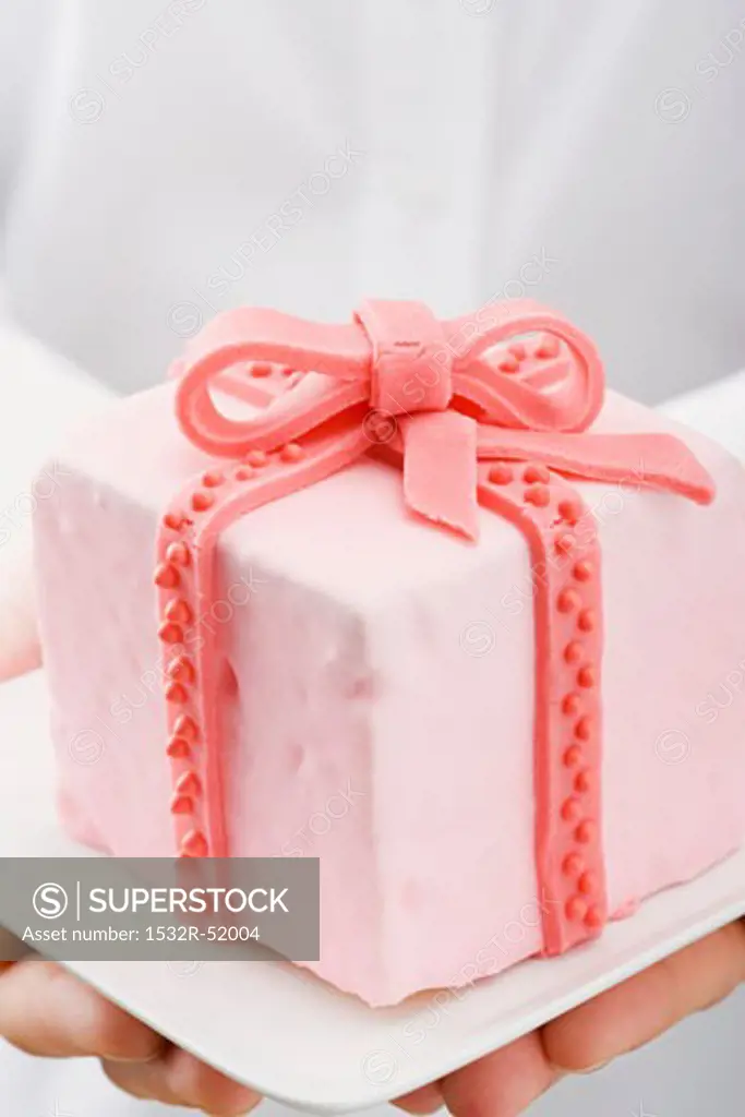 Hands holding cake with marzipan ribbon