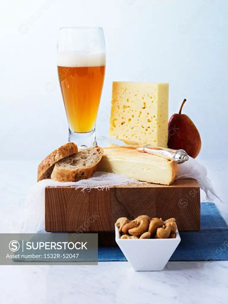 Cheese, bread, pear and wheat beer on a board