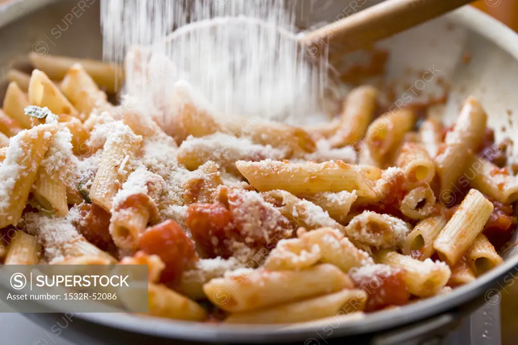 Adding Parmesan Cheese to Penne Pasta with Tomato Sauce in Saute Pan