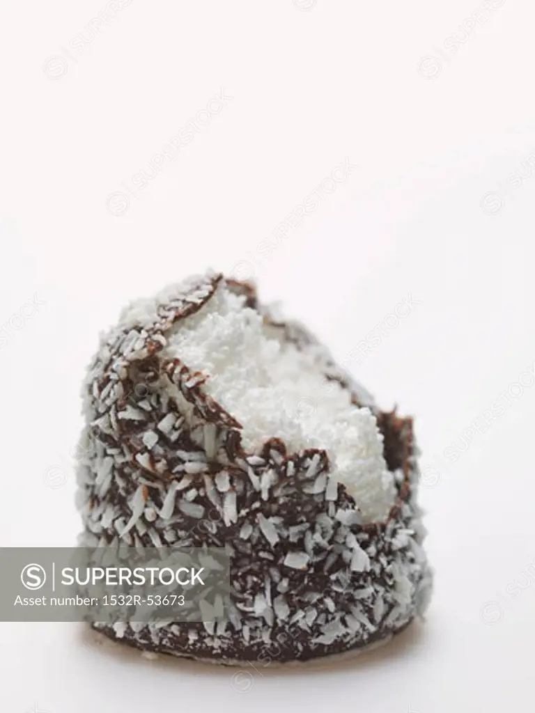 Chocolate teacake covered in grated coconut, a bite taken
